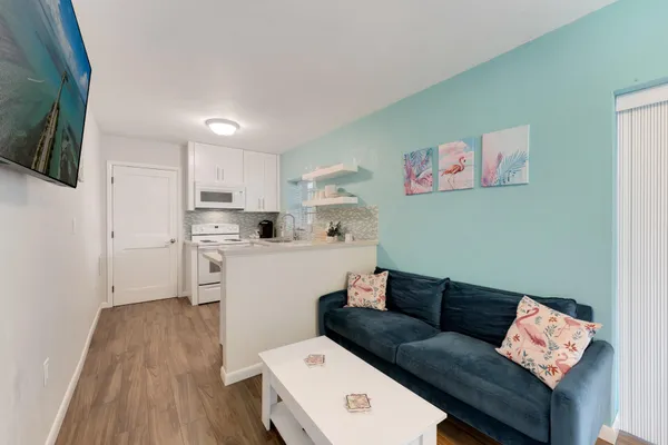 a living room with stainless steel appliances furniture and a kitchen view