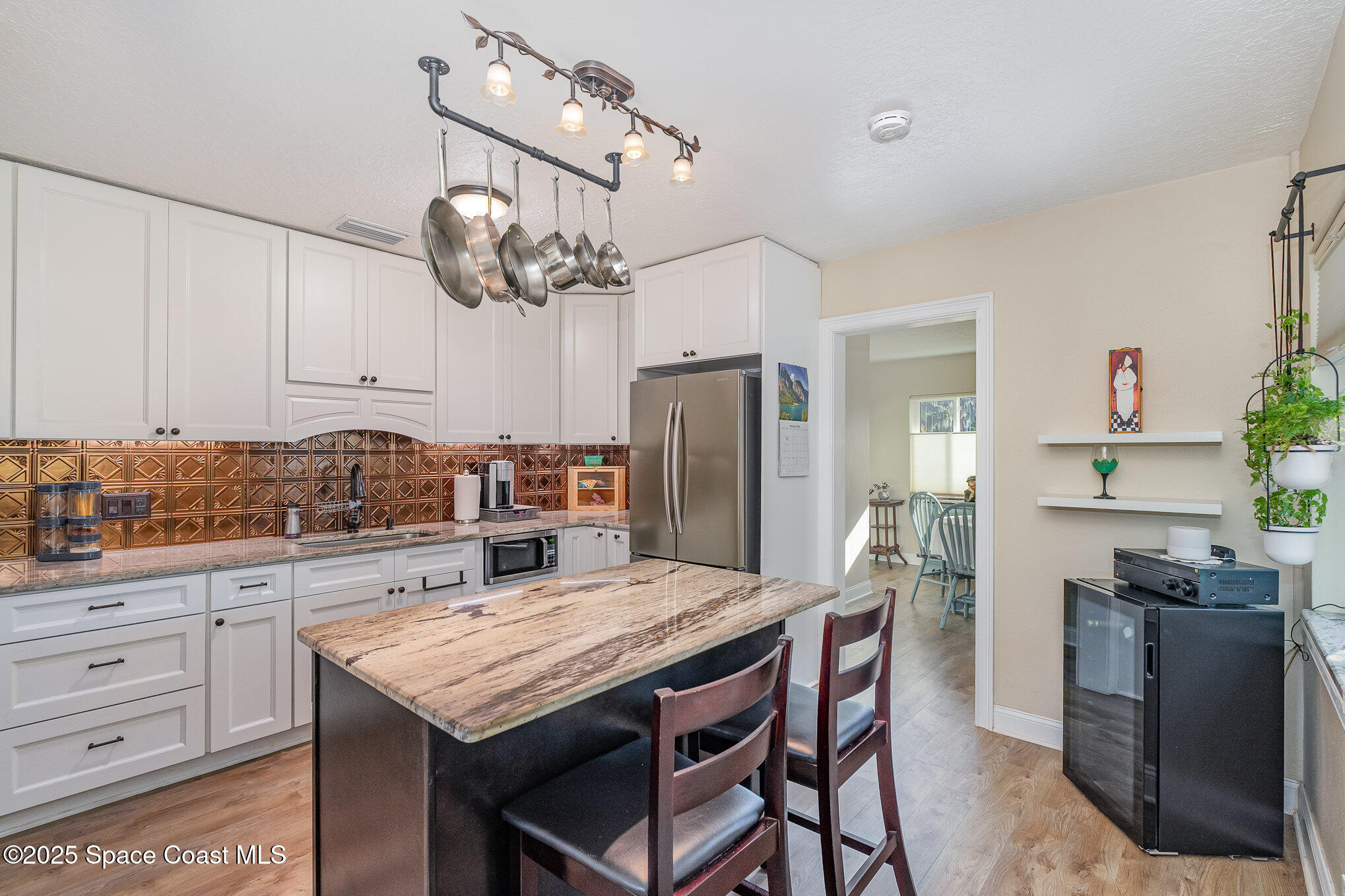 701 Espanola Way Melbourne, FL 32901 - Photo 6 of 29 a kitchen with granite countertop a table chairs stainless steel appliances and cabinets