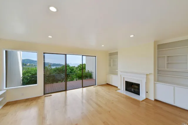 a view of empty room with floor to ceiling window and fireplace