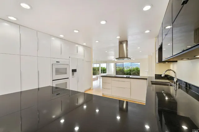 a large kitchen with stainless steel appliances a large counter top a stove and a sink