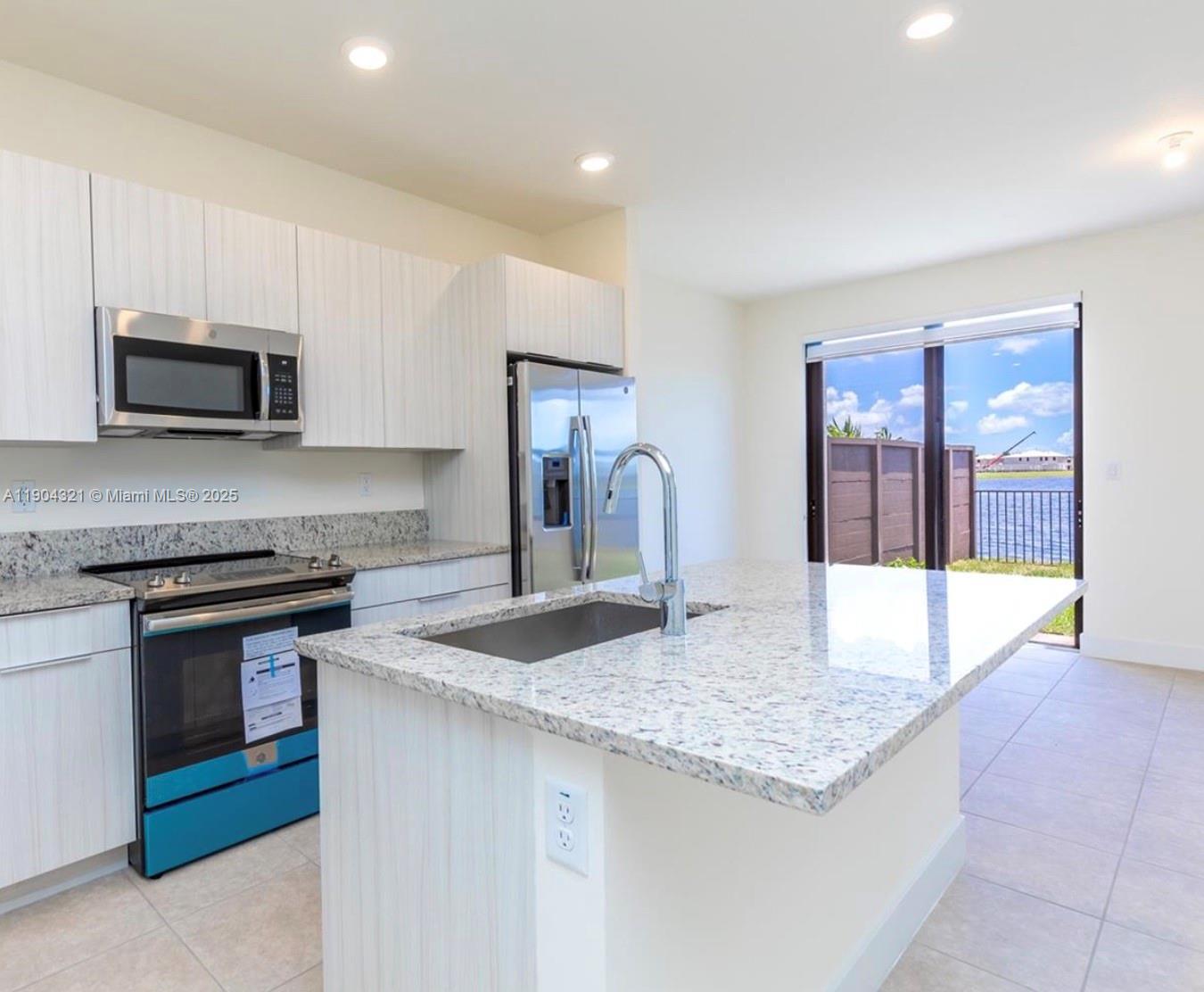 15861 Northwest 90th Court, Unit 15861 Miami Lakes, FL 33018 - Photo 16 of 31 a kitchen with kitchen island granite countertop a stove sink and microwave