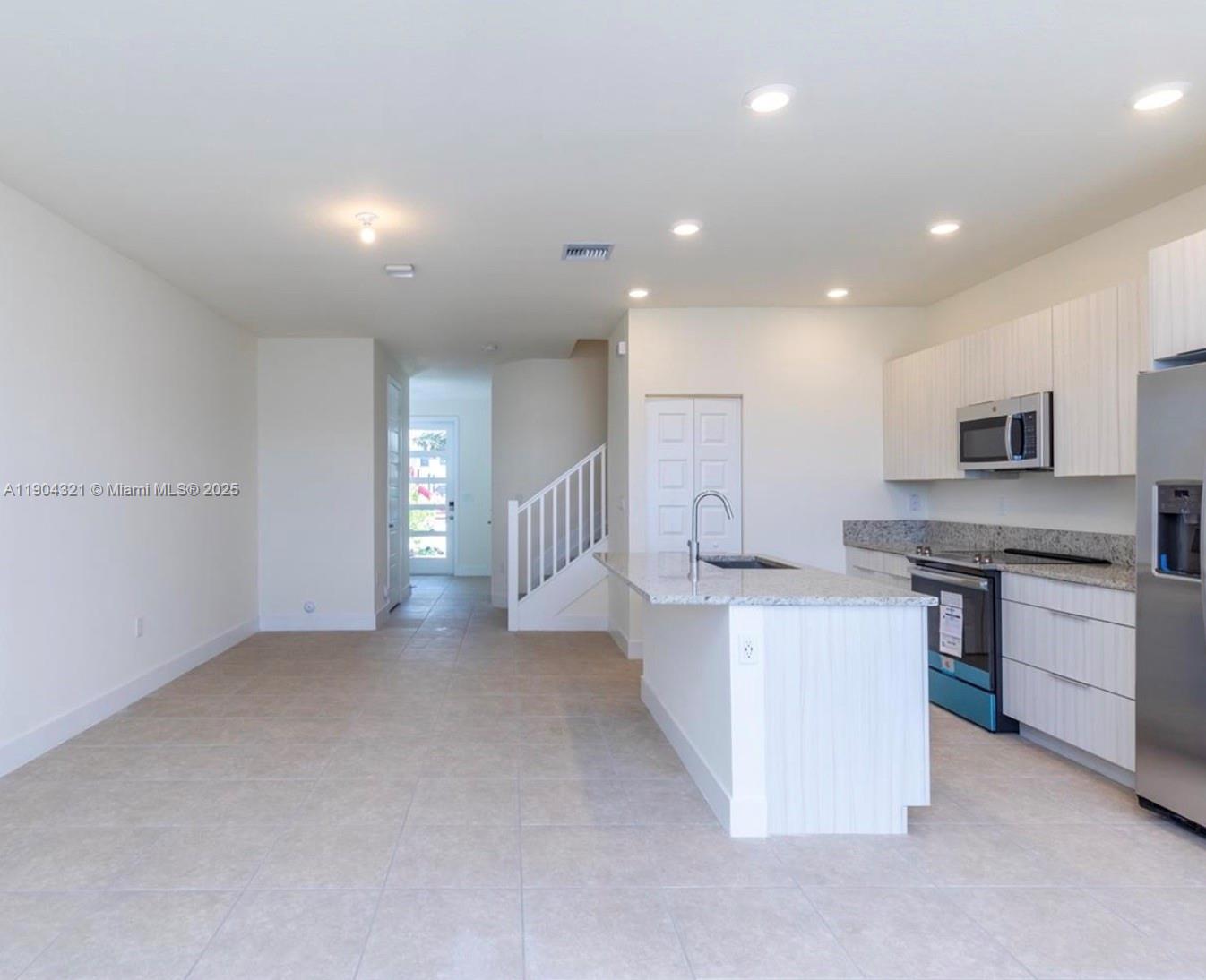 15861 Northwest 90th Court, Unit 15861 Miami Lakes, FL 33018 - Photo 18 of 31 a large white kitchen with stainless steel appliances granite countertop a stove and a sink