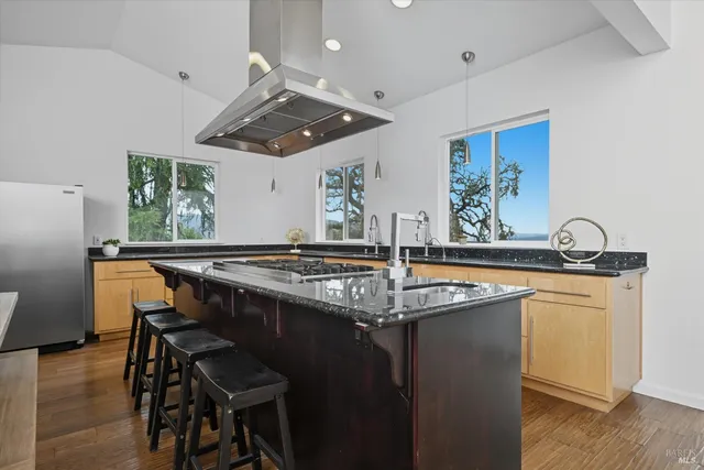 a kitchen with stainless steel appliances granite countertop a sink a stove and a wooden floors