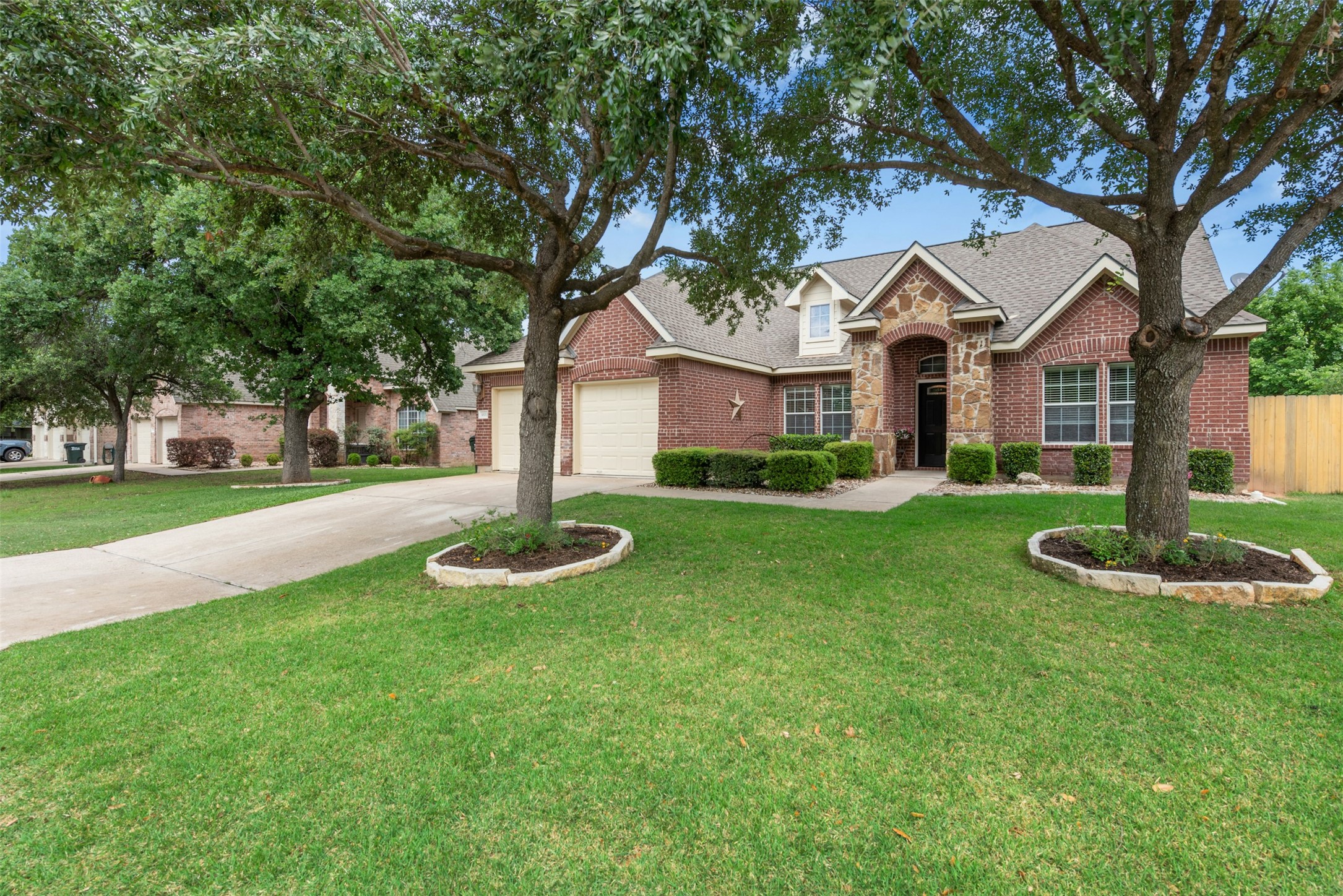 30013 Edgewood Drive Georgetown, TX 78628 - Photo 2 of 39 New Roof installed April 2026. The property features a 4-sided brick exterior with stone accents, a well-maintained lawn, and mature trees. Excellent curb appeal.