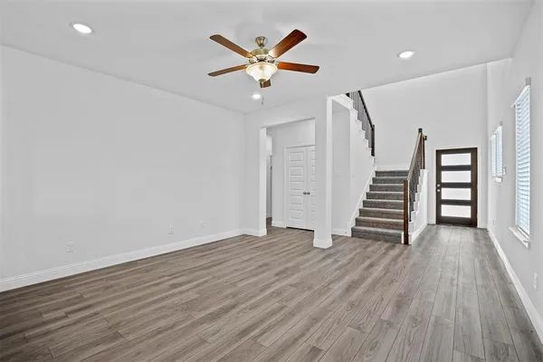 an empty room with wooden floor and a ceiling fan