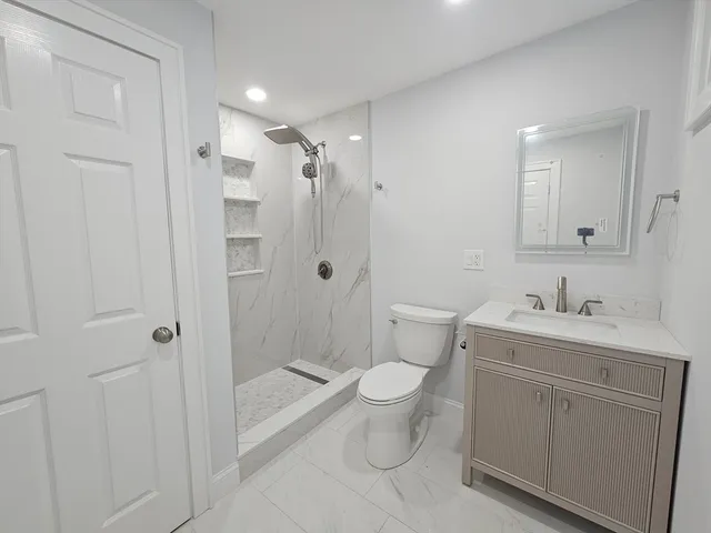 a bathroom with a granite countertop sink toilet a shower and a mirror