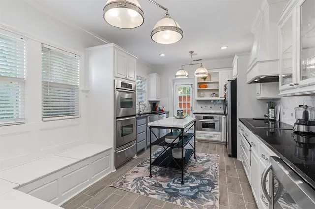 a kitchen with kitchen island granite countertop a sink cabinets and stainless steel appliances