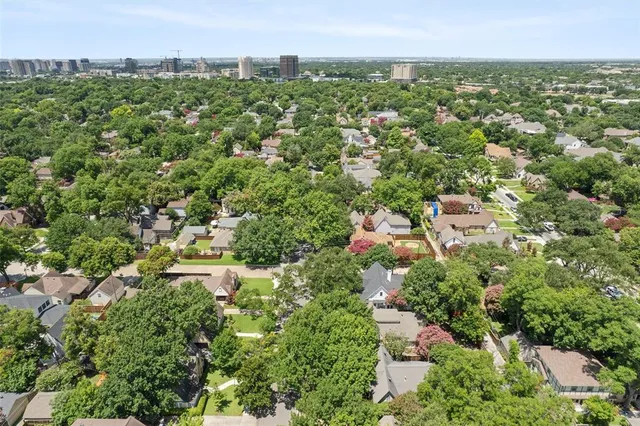 a aerial view of a house with a yard and covered with trees