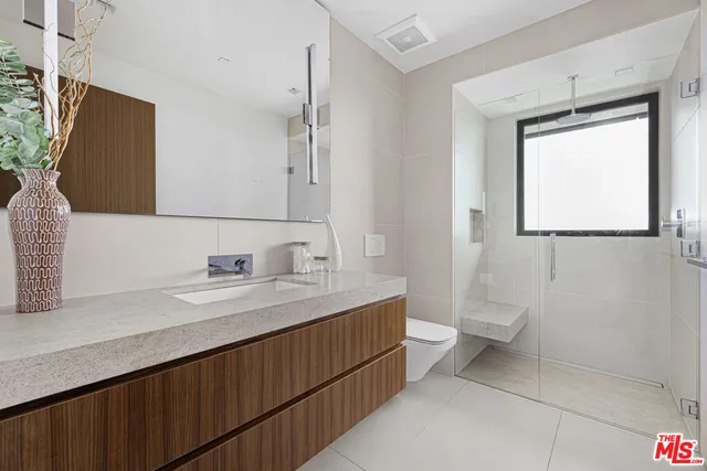 a bathroom with a granite countertop sink toilet and mirror