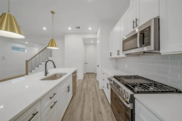 a kitchen with stainless steel appliances a sink a stove and a wooden floors