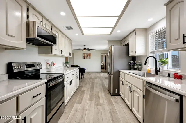 a kitchen with stainless steel appliances granite countertop lots of counter top space a sink a stove and a wooden floors