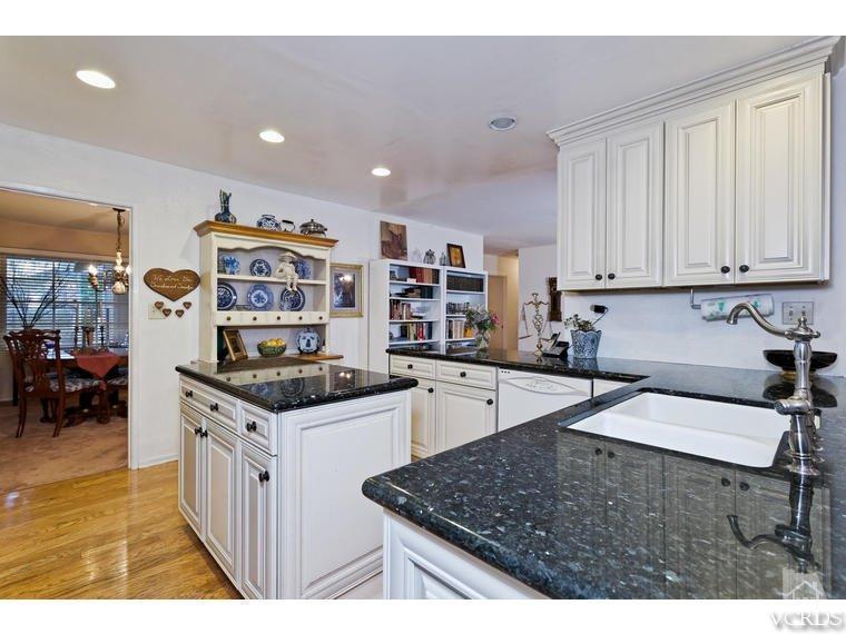 1145 Rambling Road Simi Valley, CA 93065 - Photo 7 of 30 a kitchen with stainless steel appliances granite countertop a stove top oven a sink a dining table and chairs with wooden floor