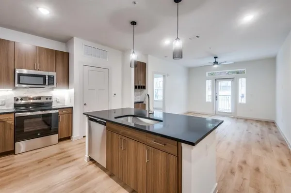 a kitchen with stainless steel appliances granite countertop a sink a stove and a wooden floors