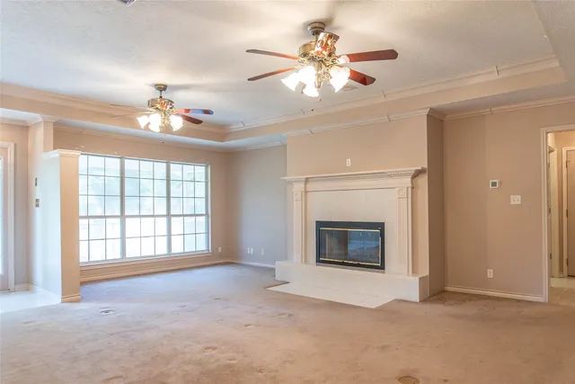 wooden floor fireplace windows and chandelier fan in an empty room