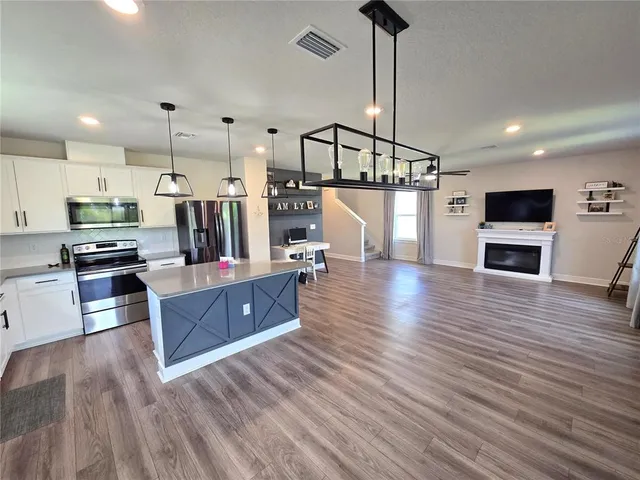 a view of a livingroom with a flat screen tv ceiling fan and wooden floor