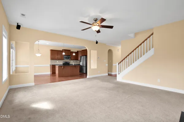 a view of a livingroom with a ceiling fan and kitchen view