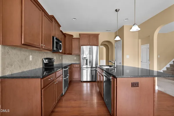 a kitchen with stainless steel appliances granite countertop a sink a stove and a refrigerator