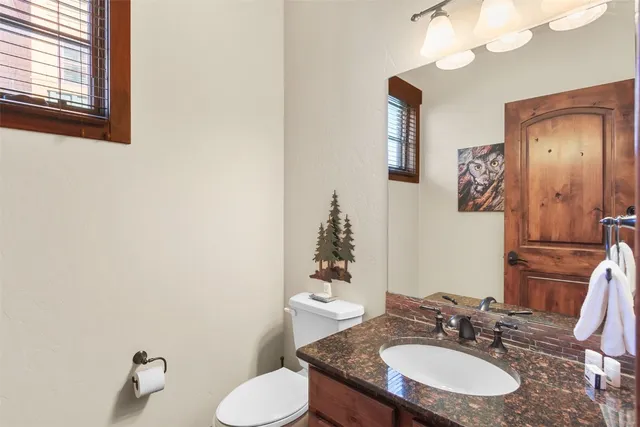 a bathroom with a granite countertop sink and a mirror with toilet