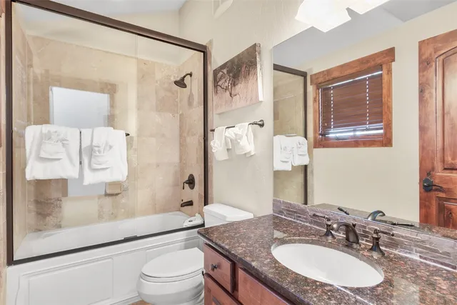 a bathroom with a granite countertop sink toilet a mirror a vanity and shower