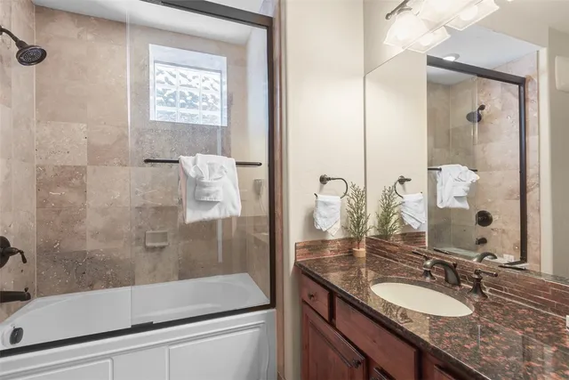 a bathroom with a granite countertop sink a mirror and shower