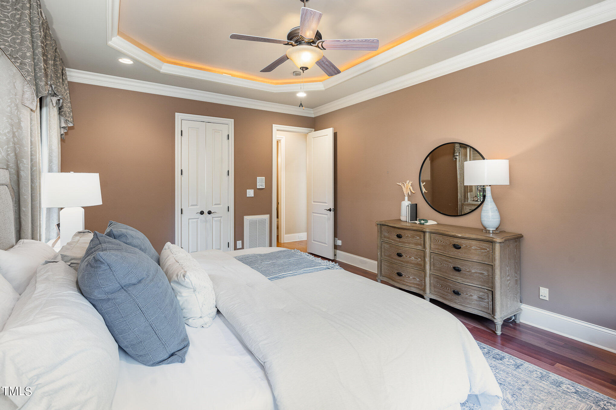 3028 Wyntree Ridge Way Raleigh, NC 27606 - Photo 15 of 39 a bedroom with a bed a mirror on dresser and a chandelier