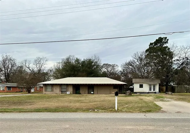 a view of a house with a yard and large trees