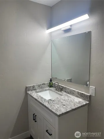 a bathroom with a granite countertop sink and a mirror