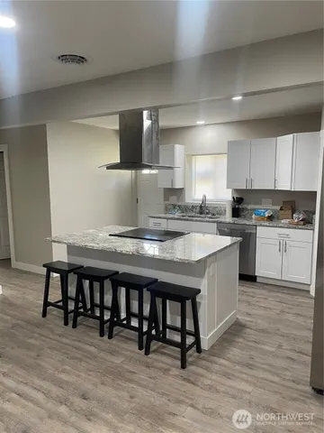 a kitchen with stainless steel appliances granite countertop a table chairs sink and cabinets