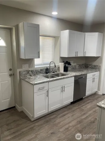 a kitchen with granite countertop white cabinets sink and stainless steel appliances