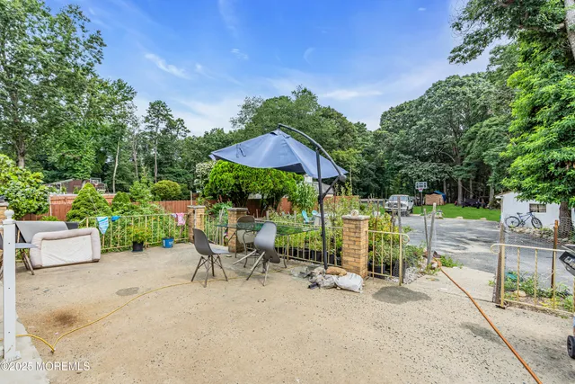 a view of a patio with table and chairs potted plants and large tree