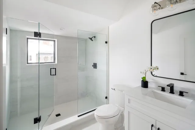 a bathroom with a shower sink vanity mirror and toilet