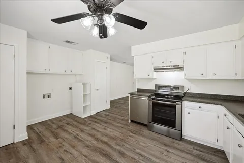 a kitchen with stainless steel appliances a stove a sink and white cabinets