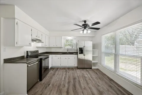 a kitchen with a white cabinets and wooden floor