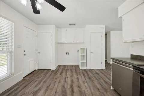 a view of kitchen and empty room with wooden floor