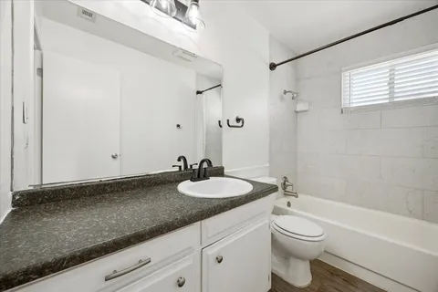 a bathroom with a granite countertop sink toilet a mirror and bathtub