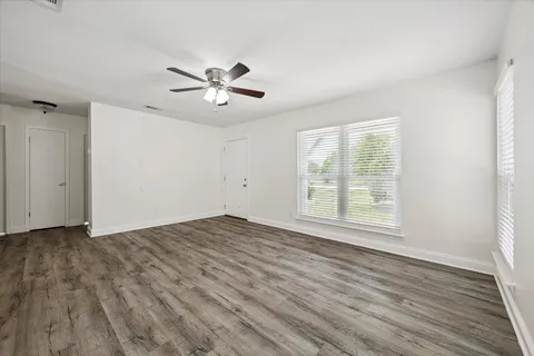 a view of empty room with wooden floor and fan