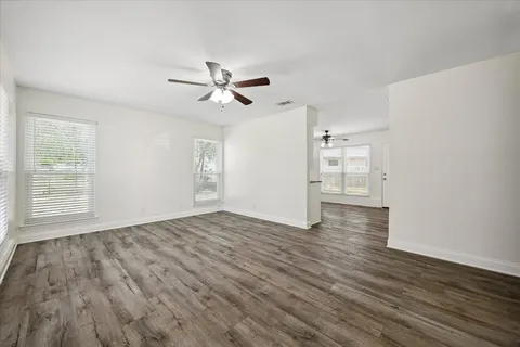 a view of empty room with wooden floor and ceiling fan