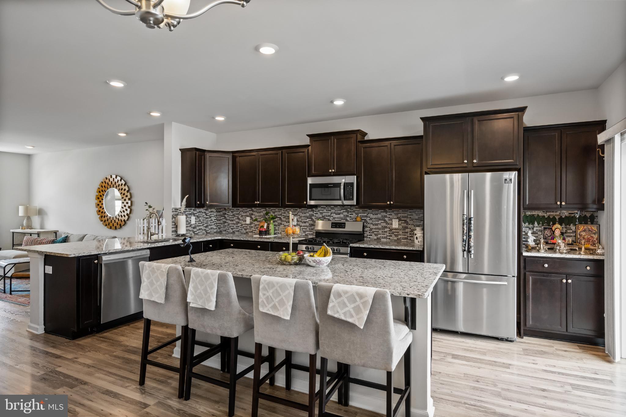 6 Rome Way Mount Laurel, NJ 08054 - Photo 13 of 28 a kitchen with stainless steel appliances granite countertop a refrigerator a stove top oven a sink dishwasher and chairs with wooden floor