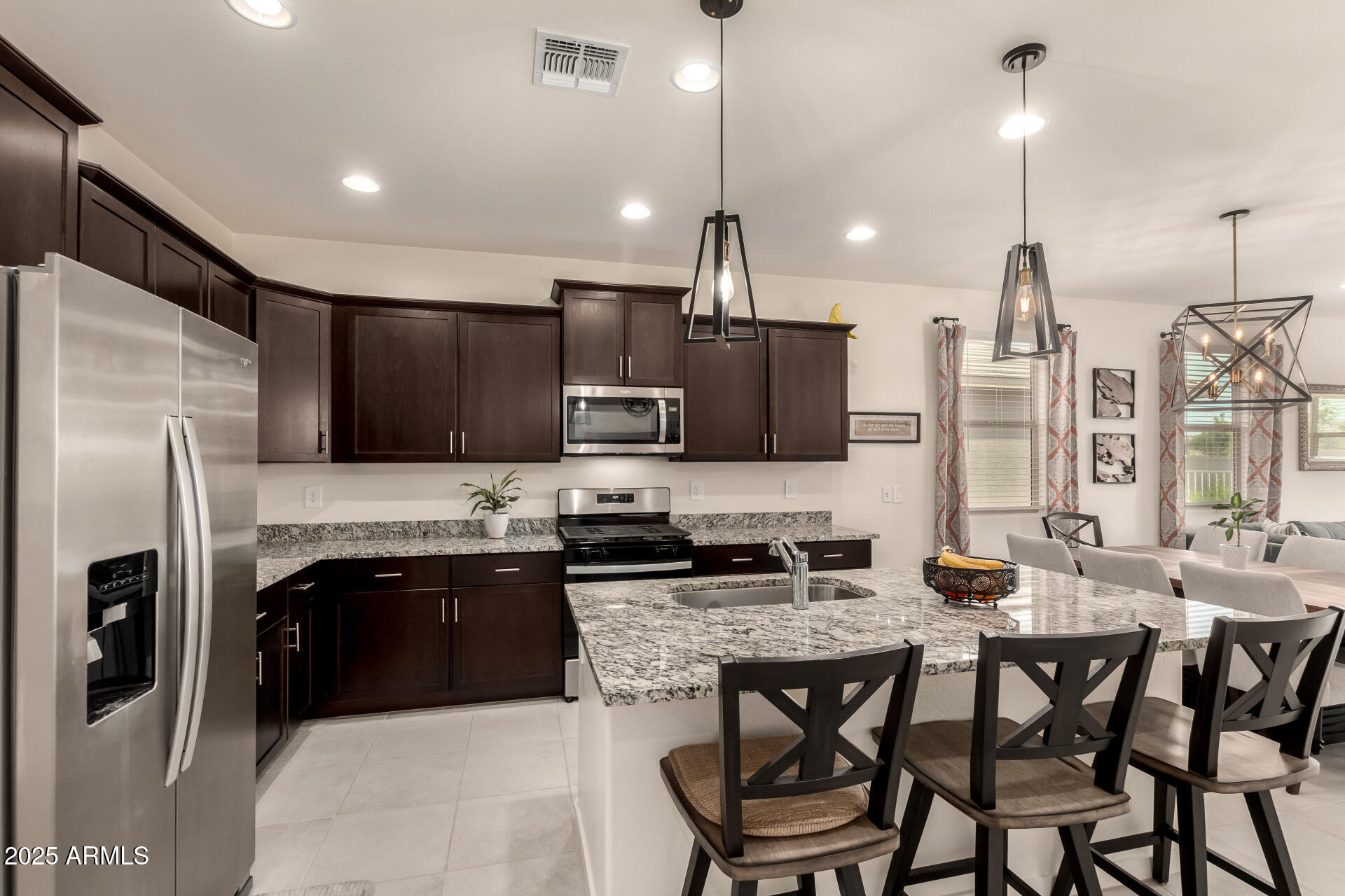 20485 North Candlelight Road Maricopa, AZ 85138 - Photo 12 of 26 a kitchen with stainless steel appliances kitchen island granite countertop a stove a refrigerator a oven a sink with a dining table and chairs