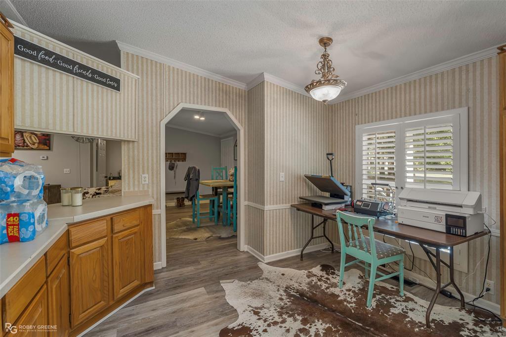8273 Godfrey Road Shreveport, LA 71129 - Photo 11 of 27 Wood-finish flooring throughout, archway entryway, window with plantation shutters, crown molding, and a built-in pass-through window