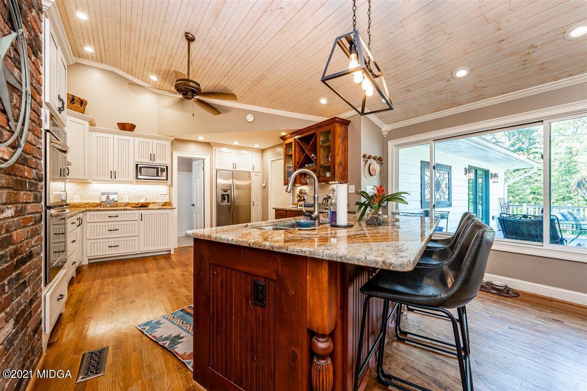 7798 Zebulon Road Macon, GA 31220 - Photo 6 of 35 a kitchen with stainless steel appliances granite countertop a sink a stove and chairs with wooden floor