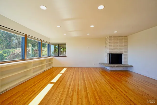 a view of empty room with wooden floor and fireplace