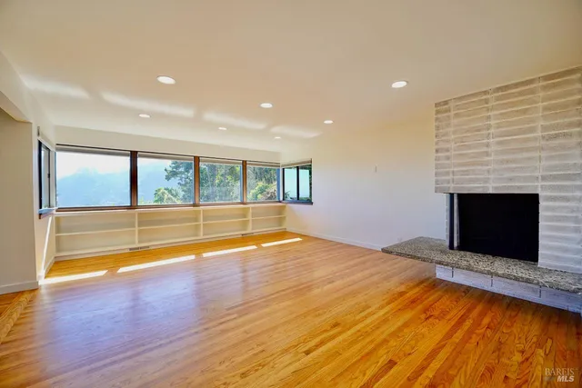 a view of empty room with wooden floor and fireplace