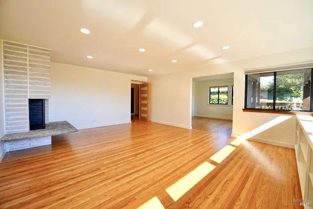 a view of empty room with wooden floor and fireplace
