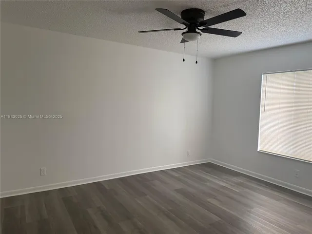 an empty room with wooden floor a ceiling fan and windows