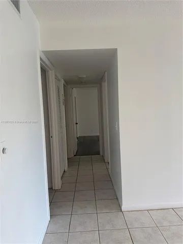 a view of an empty room and chandelier fan