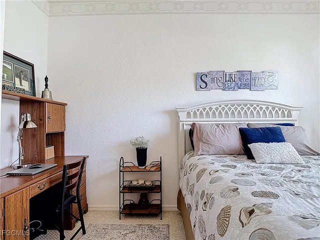 a bedroom with a bed and a computer on a dresser