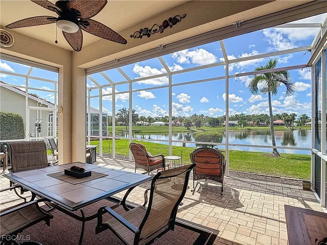 a living room with patio furniture and floor to ceiling windows