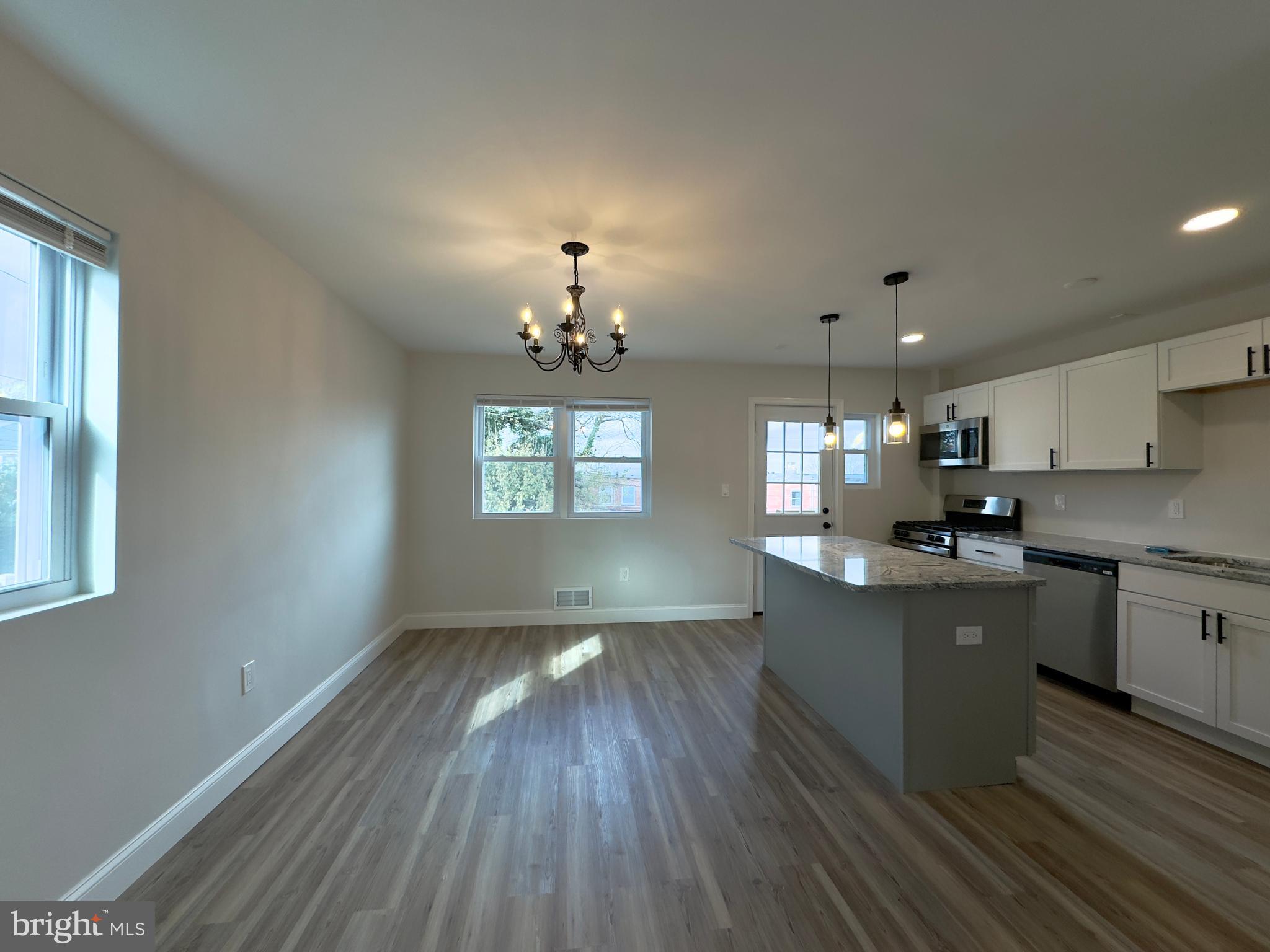 5430 Whitlock Road Baltimore, MD 21229 - Photo 24 of 30 a kitchen with granite countertop a stove top oven a sink dishwasher and white cabinets with wooden floor