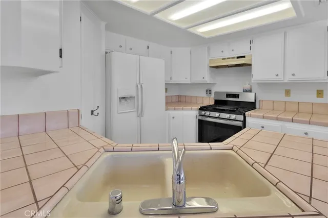 a kitchen with stainless steel appliances kitchen island granite countertop a sink and white cabinets